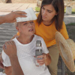 A man and woman apply ice and use a hat to fan a woman suffering from heatstroke.