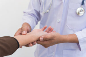 A doctor holds a patient’s hand and examines her wrist.
