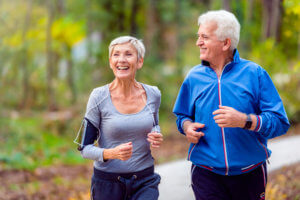 Smiling older couple exercise in a park after receiving treatment for back pain.