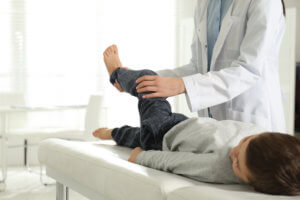 Orthopedic surgeon examines a young boy’s leg for signs of juvenile arthritis.