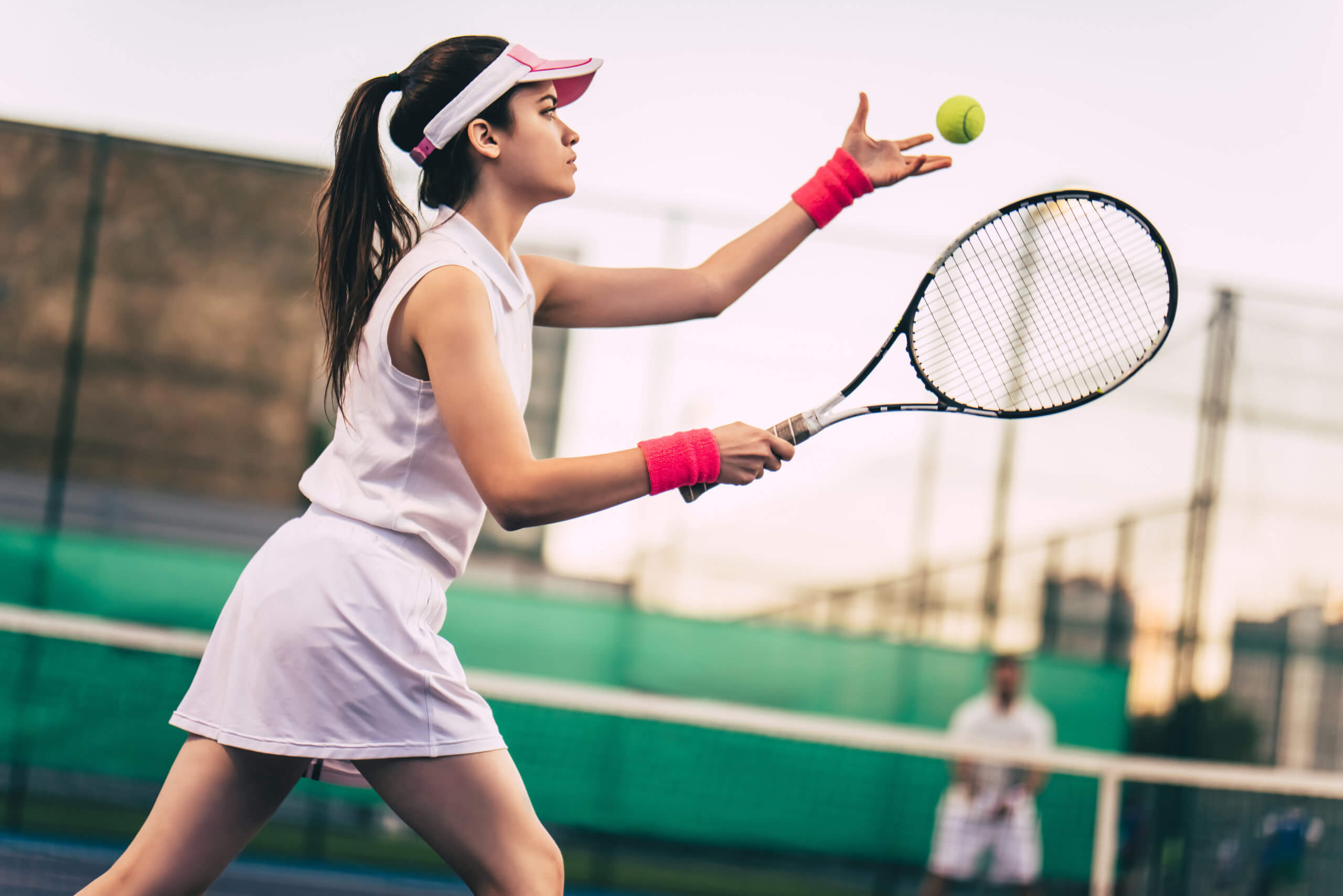 A young woman prepares to serve the ball on a tennis court during a game.