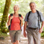 Happy senior couple enjoys a walk together in a sunny wooded park.