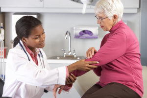 Doctor examining elderly patient with joint pain in the elbow