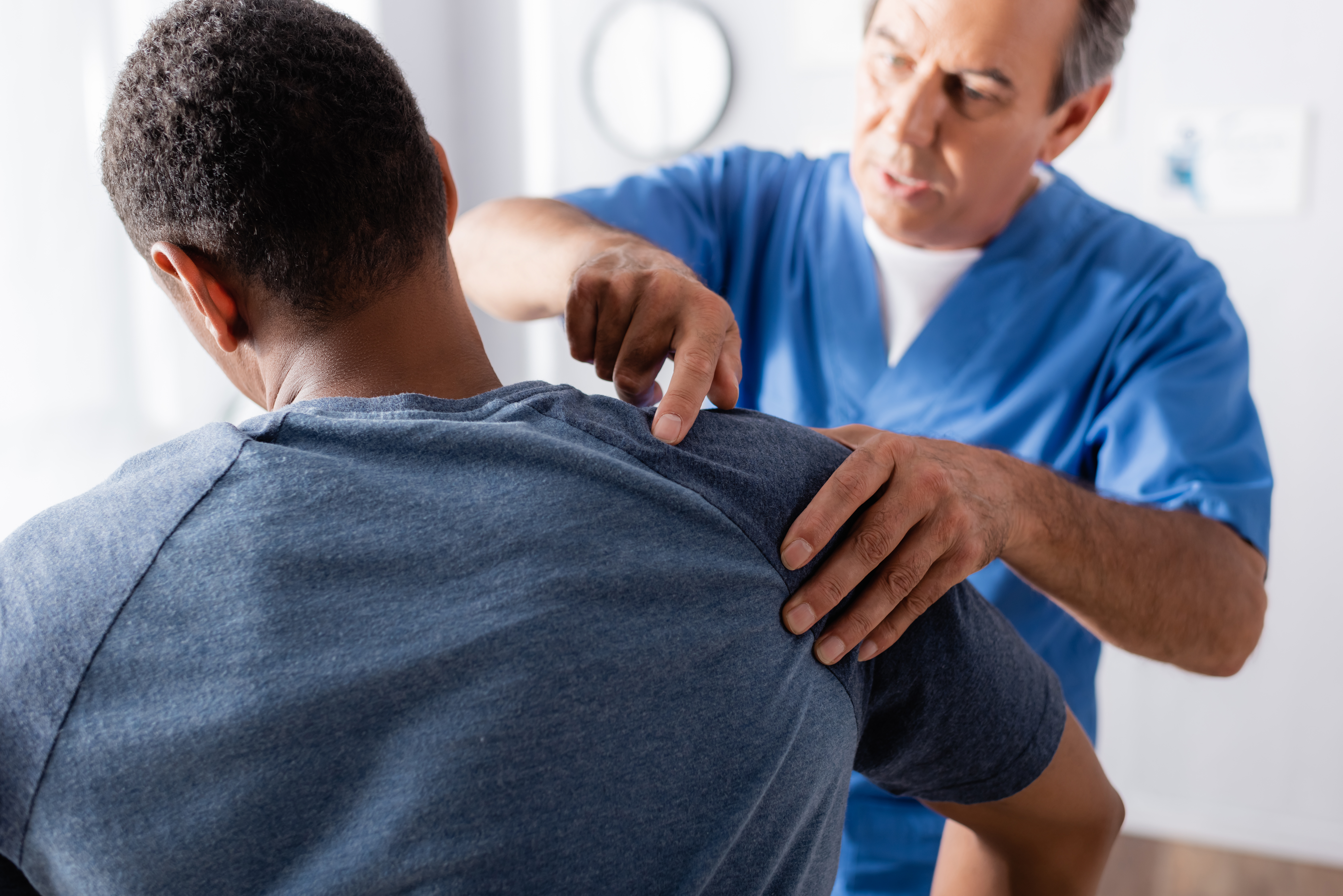  An orthopedic doctor examines a patient’s shoulder injury. 