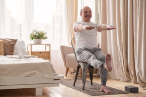 Older person at home doing strength and mobility exercises in a chair.