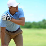 Young male golfer has shoulder pain after a swing on the golf course.