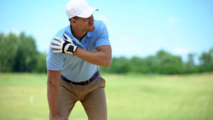 Young male golfer has shoulder pain after a swing on the golf course.