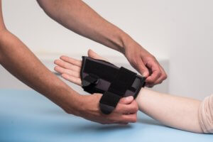 A hand specialist places a thumb brace on a patient’s hand.