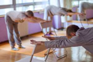 A group in a studio perform chair yoga exercises.