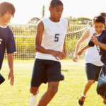 A group of four teenage boys plays soccer outdoors.
