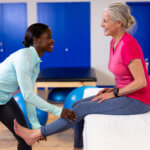 A physical therapist helping patient with leg exercises.