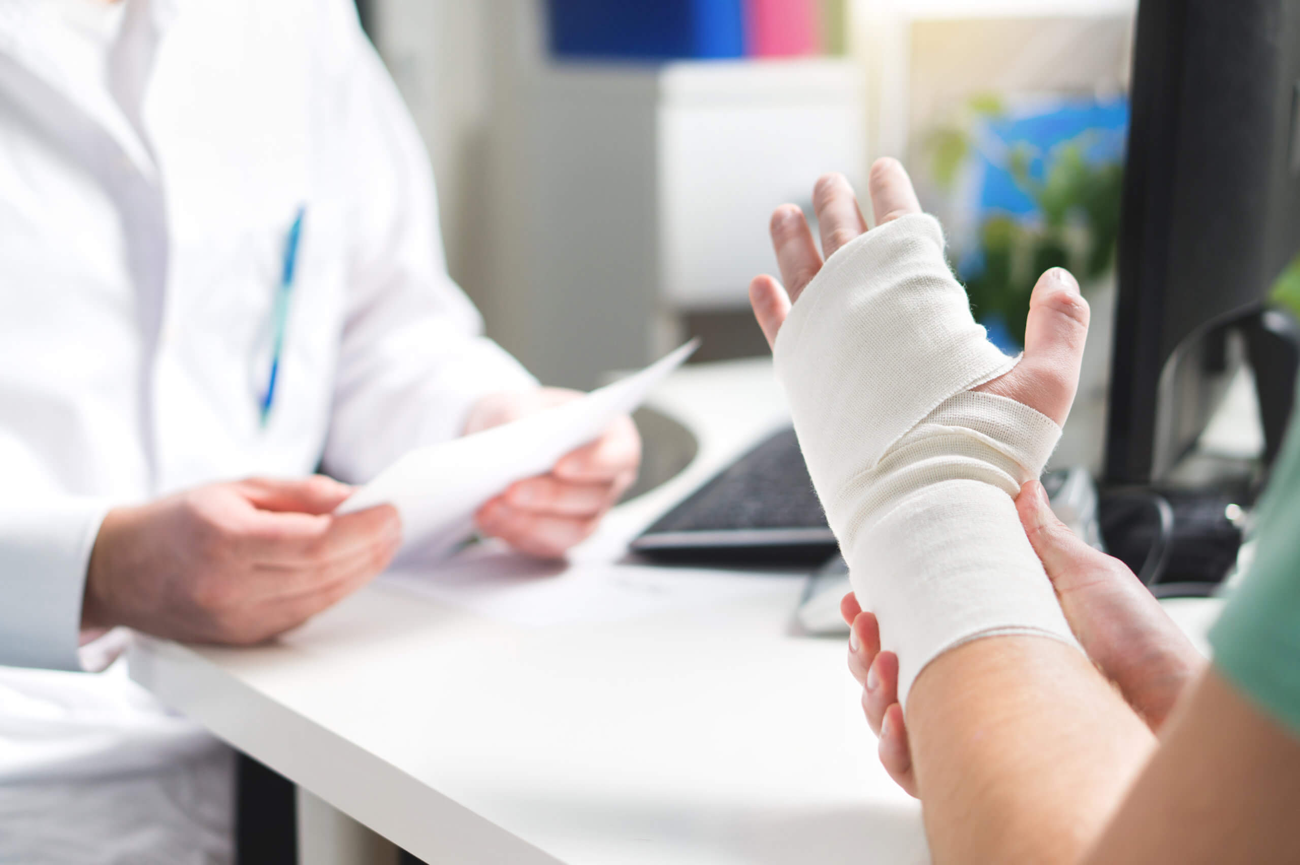 Person with wrist bandaged after an injury talks to a doctor in the office. 
