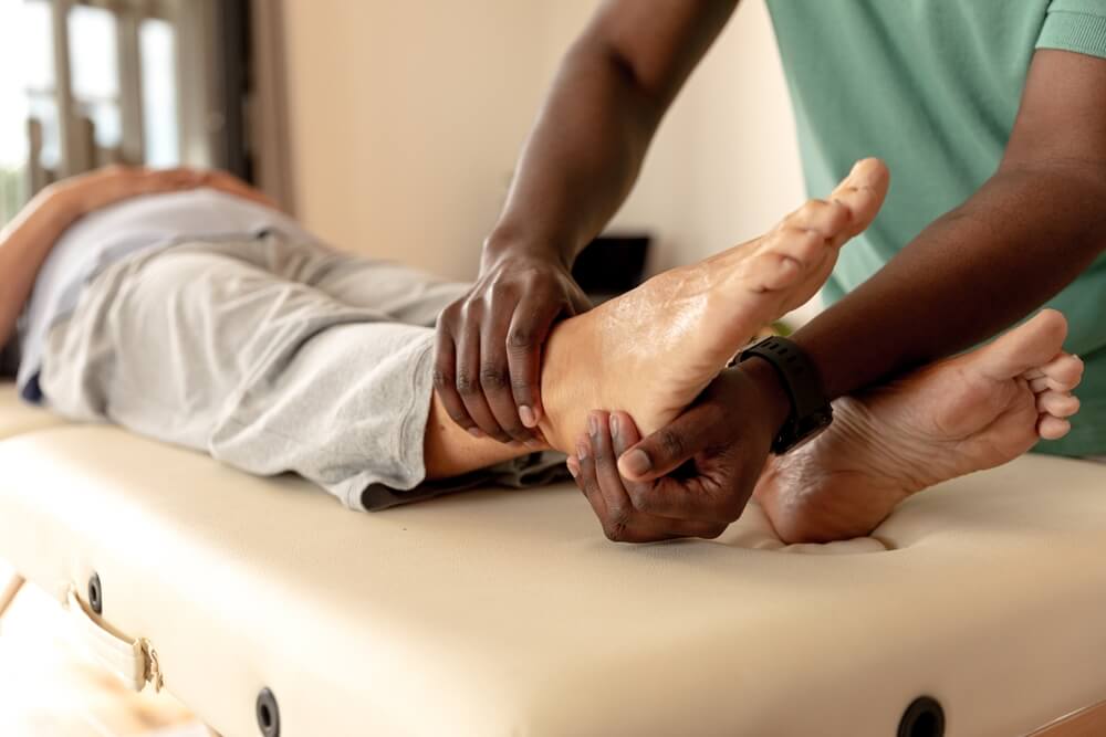 A physical therapist manipulates a patient’s ankle as he lies on a table. 