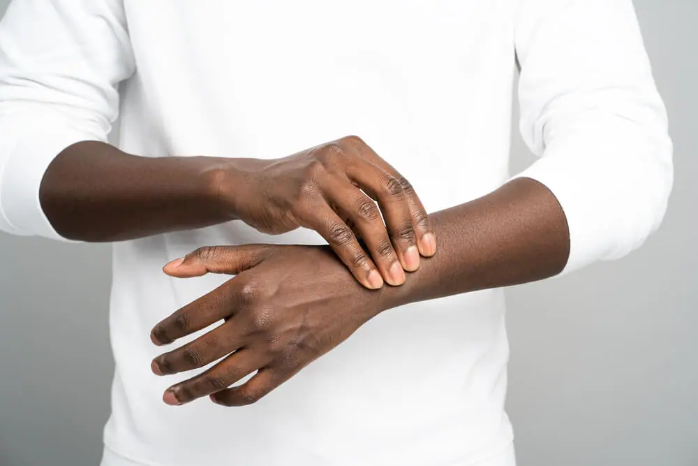  Man in white shirt holds wrist in pain. 