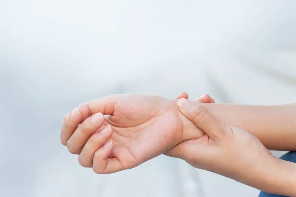  Woman holds her wrist in pain because of carpal tunnel. 