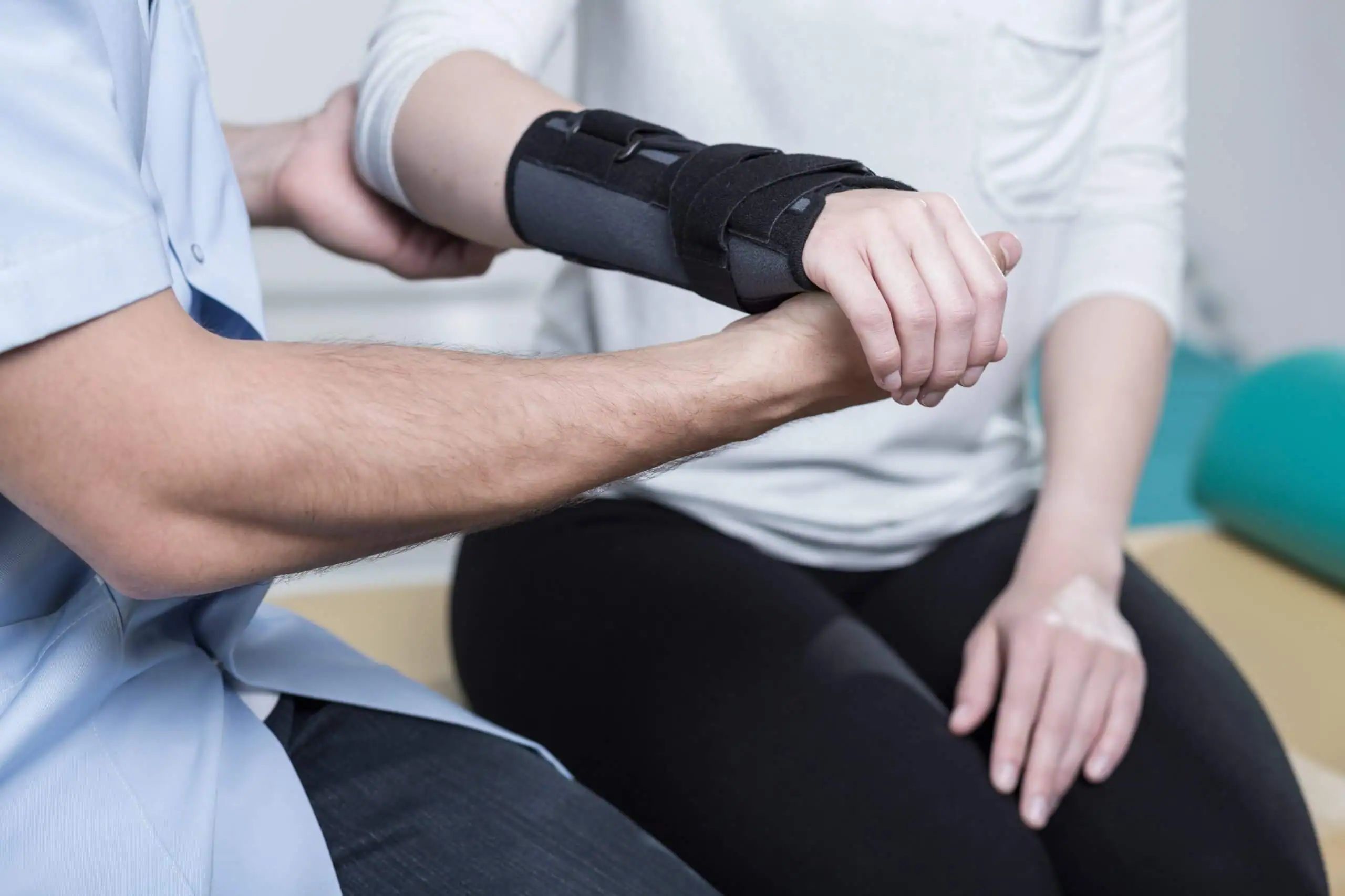 A male medical professional holds a female patient’s wrist in a splint.