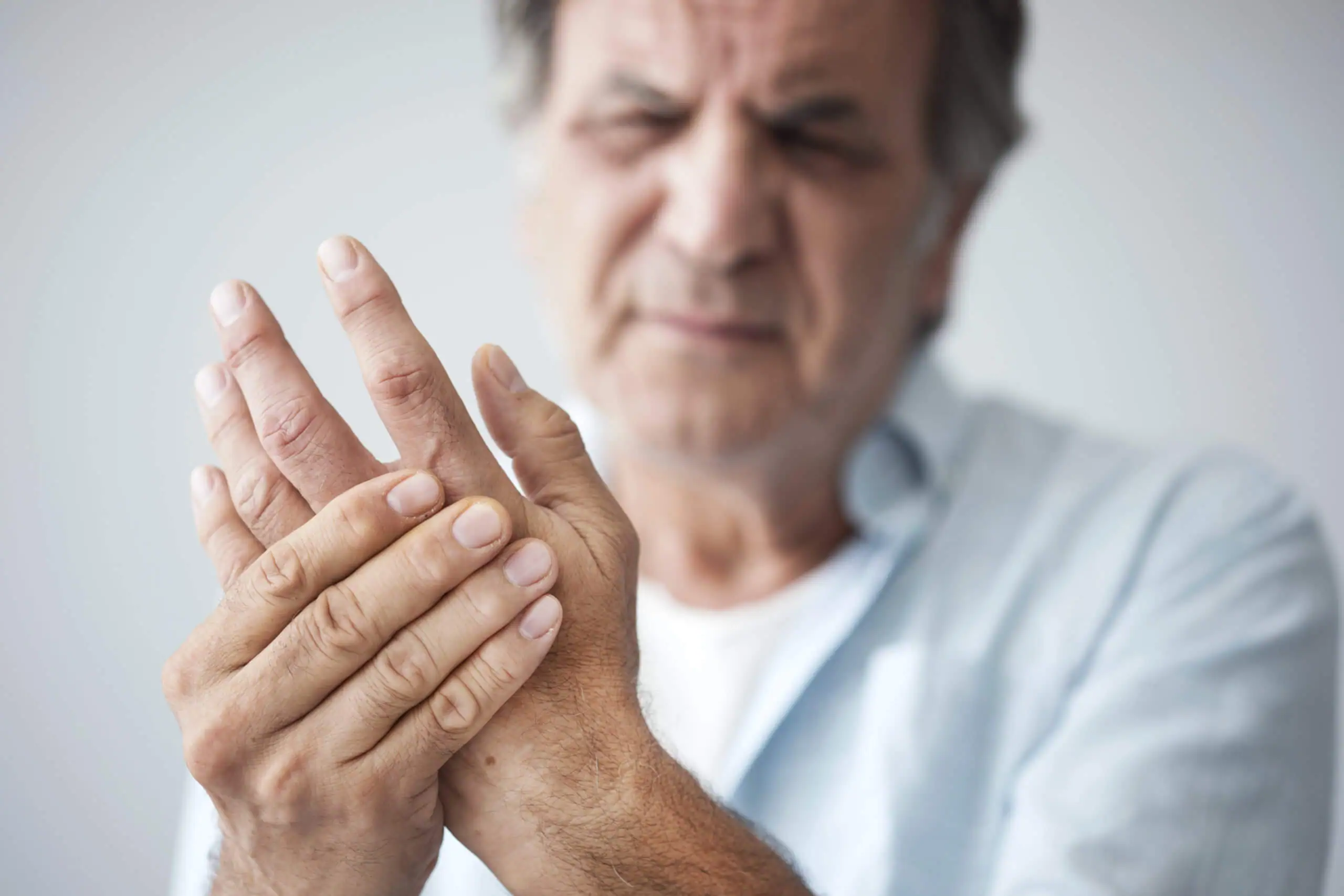 A man holds his hand in pain while suffering from Dupuytren’s contracture. 