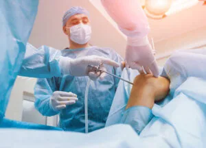 Orthopedic surgeons perform arthroscopic knee surgery on an adult patient.