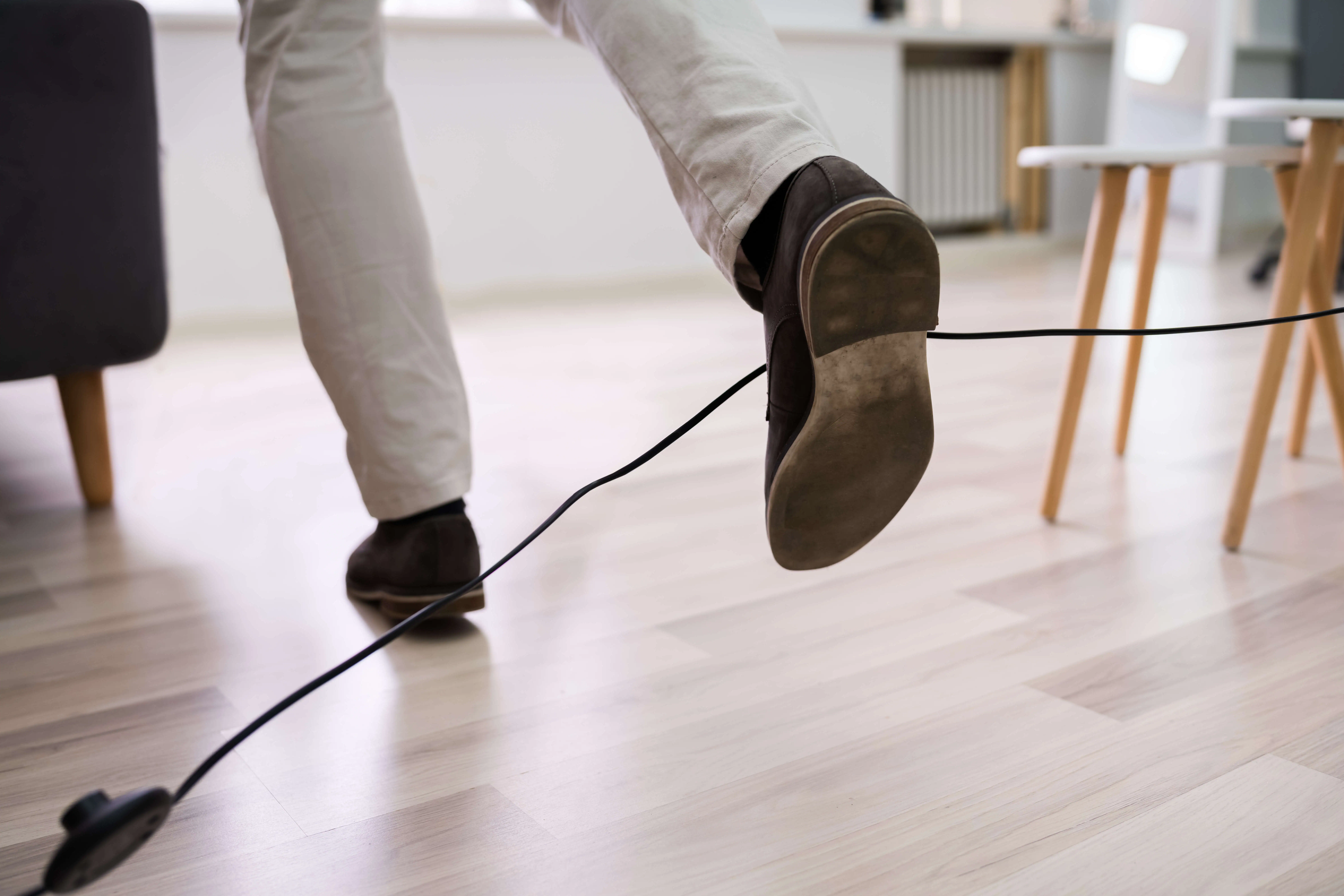 Close up of a worker tripping over a cord at work. 